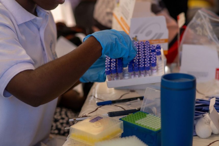 Profissional de saúde organiza tubos de ensaio em um laboratório.