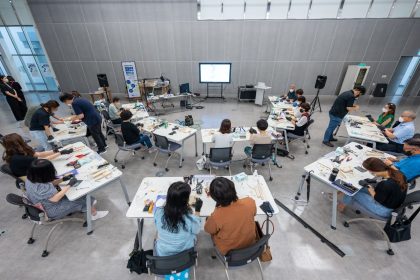 Estudantes participam de uma oficina prática em sala de aula, utilizando equipamentos tecnológicos.