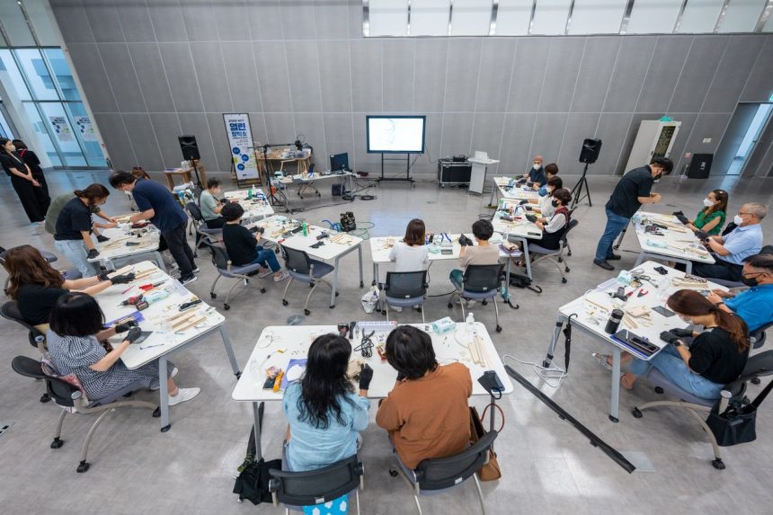 Estudantes participam de uma oficina prática em sala de aula, utilizando equipamentos tecnológicos.