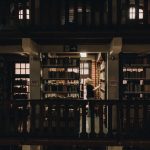 Pessoa lendo em uma biblioteca de São Paulo, entre estantes repletas de livros