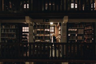 Pessoa lendo em uma biblioteca de São Paulo, entre estantes repletas de livros