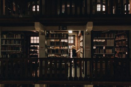 Pessoa lendo em uma biblioteca de São Paulo, entre estantes repletas de livros