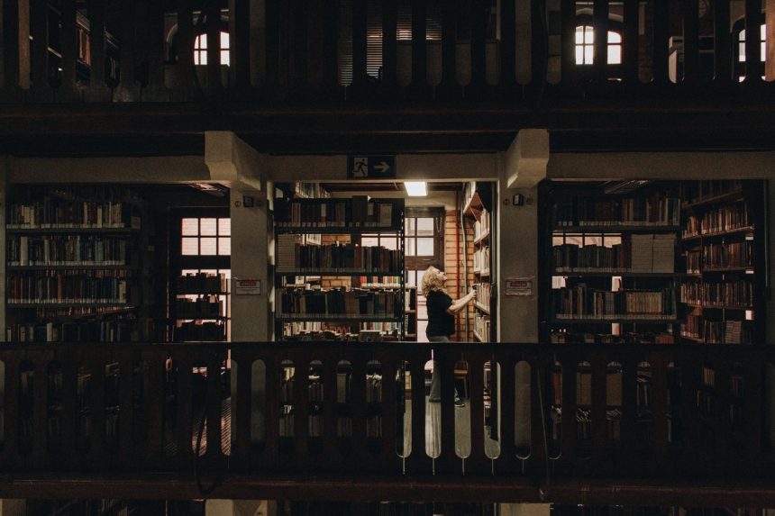Pessoa lendo em uma biblioteca de São Paulo, entre estantes repletas de livros