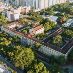 Vista aérea de um campus universitário histórico cercado por áreas verdes.