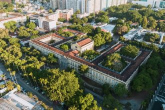 Vista aérea de um campus universitário histórico cercado por áreas verdes.