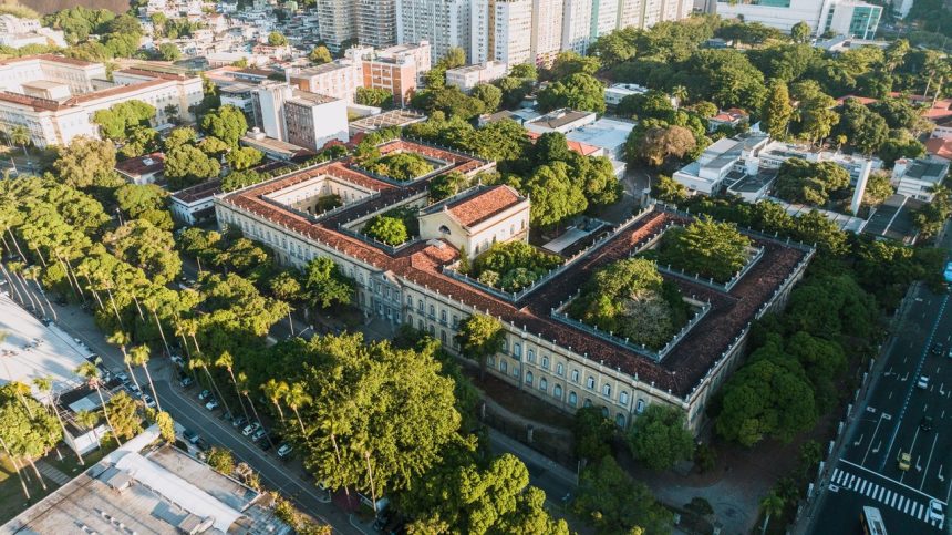 Vista aérea de um campus universitário histórico cercado por áreas verdes.