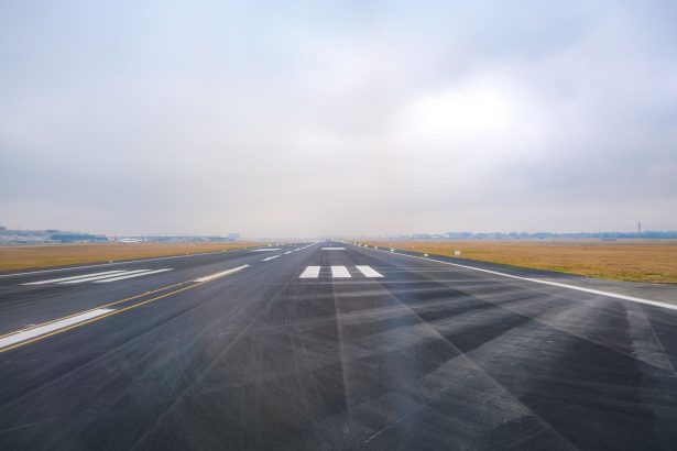 Pista de aeroporto vazia se estende ao longe sob céu enevoado.