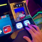Mão interage com botões de uma interface colorida de máquina caça-níqueis.