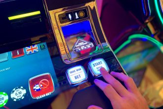 Mão interage com botões de uma interface colorida de máquina caça-níqueis.