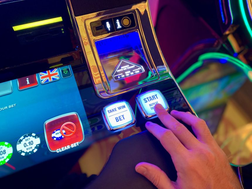 Mão interage com botões de uma interface colorida de máquina caça-níqueis.